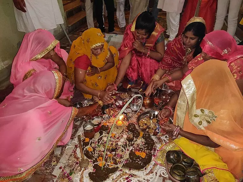 On Bhai dooj, women sitting in a circle worship a mound of cow dung and Ganesh and listen to the story On Bhai dooj, women sitting in a circle worship a mound of cow dung and Ganesh and listen to the story