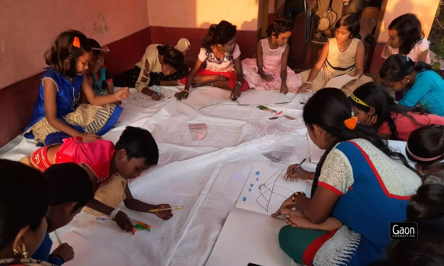 Sitting around him on a white sheet spread out on the floor, children pay close attention to Mohanti who sits on a bench and paints on an easel. Sitting around him on a white sheet spread out on the floor, children pay close attention to Mohanti who sits on a bench and paints on an easel.